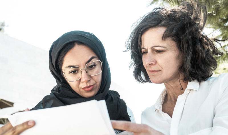 two middle eastern women looking at document