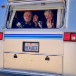 man and woman waving from back window of van