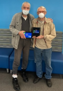two mature men holding electronic devices