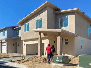 Newly constructed homes and two people walking in to view them.