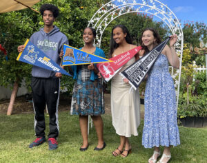 four young happy adults holding college branded pennants