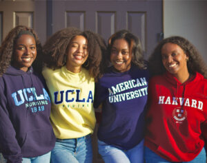 four young women wearing college branded sweatshirts