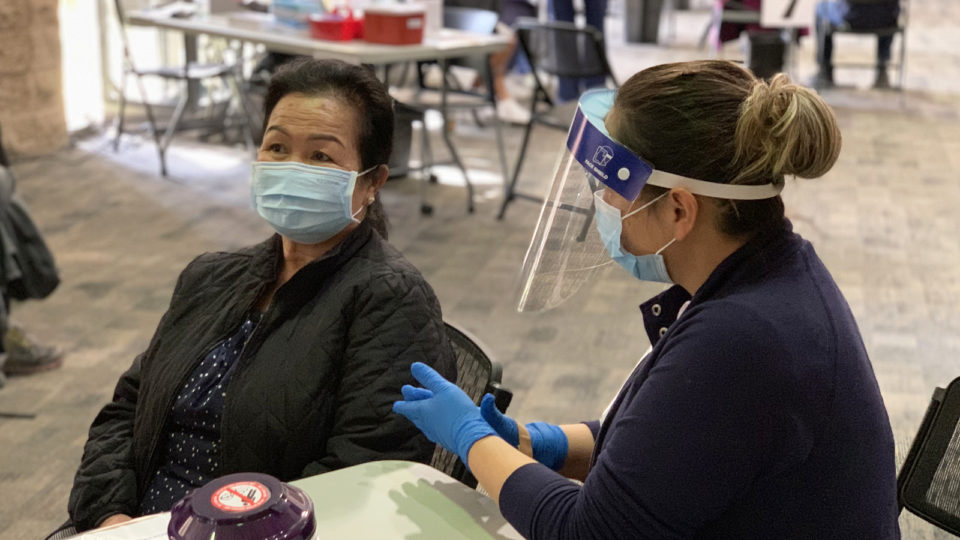 San Diego County image of Asian woman receiving Covid-19 vaccine by healthcare worker